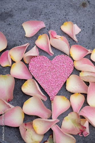 pink and light flowers on concrete background as voucher or card background with pink chocolate heart with sugar pearls