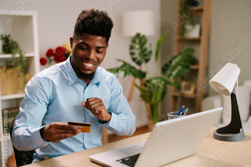 Young man uses a credit card through a laptop on the Internet