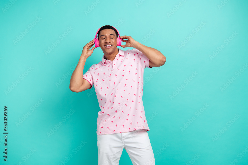 Portrait of peaceful positive man closed eyes arms touch headphones isolated on cyan color background Portrait of peaceful positive man closed eyes arms touch headphones isolated on cyan color background