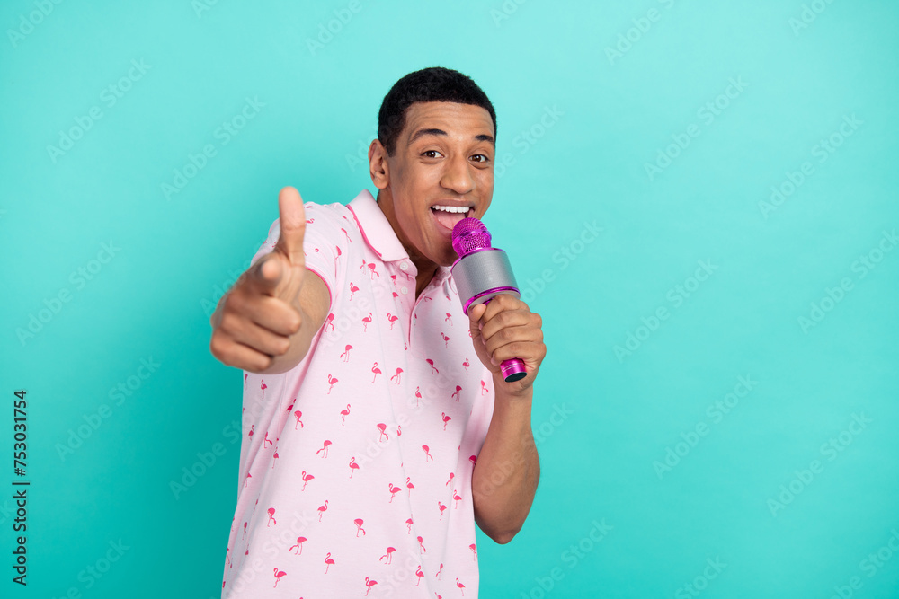 Photo of positive person hold microphone sign point finger camera you empty space ad isolated on teal color background Photo of positive person hold microphone sign point finger camera you empty space ad isolated on teal color background