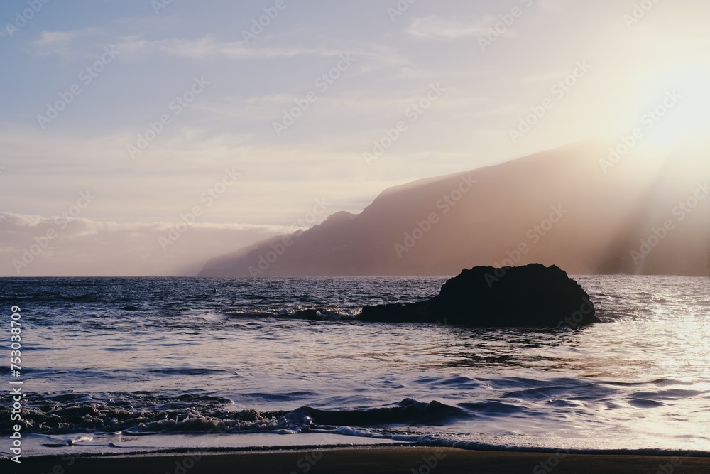 Beautiful black sand beach in Seixal, Madeira Island, Portugal. Huge hills covered by tropical forest in the background. Summer vacation destination. Portuguese landscape