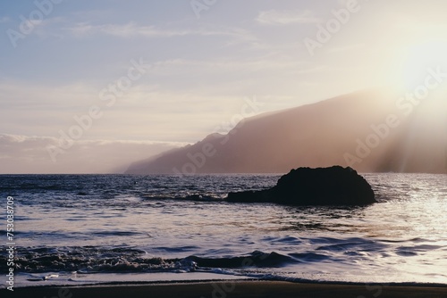 Beautiful black sand beach in Seixal, Madeira Island, Portugal. Huge hills covered by tropical forest in the background. Summer vacation destination. Portuguese landscape