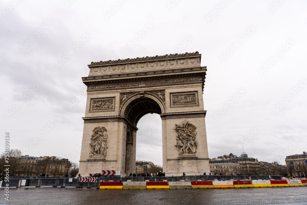 The Arc de Triomphe is a large, white and gray arch with a red and yellow border
