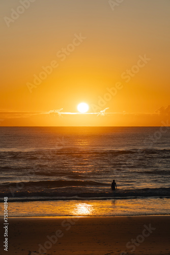 Silhouette of an unrecognizable woman entering the ocean water early in the day © Uri Prat