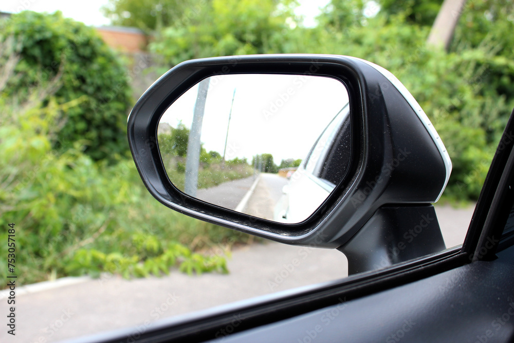 Rear-view mirror on a modern car. Rearview mirror with reflection in it. Rear view mirror car on the road. Wing mirror of a modern car with nature street.