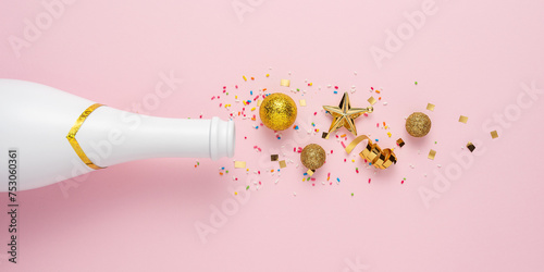 Creative layout with Champagne bottle and gold glitter decoration. Minimal New Year greeting card party pink background. Flat lay composition.