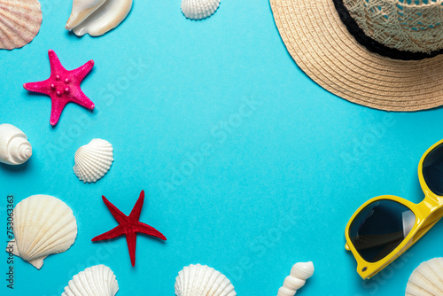 Creative composition with seashells  hat and yellow sunglasses on blue background. Summer minimal concept.