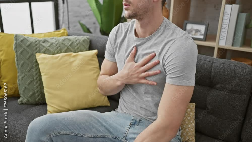 Handsome man in casual wear feeling chest pain sitting in modern living room
