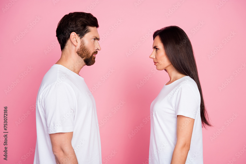 Photo portrait of lovely young couple look each other frowning angry dressed stylish white garment isolated on pink color background Photo portrait of lovely young couple look each other frowning angry dressed stylish white garment isolated on pink color background