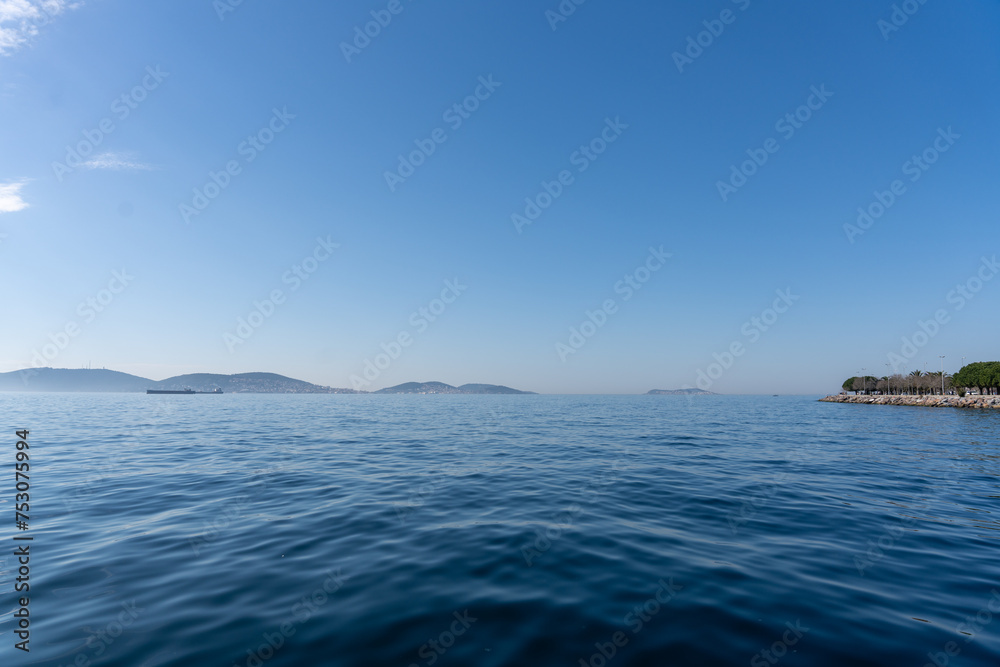 The ocean is calm and blue, with a few boats in the distance The ocean is calm and blue, with a few boats in the distance