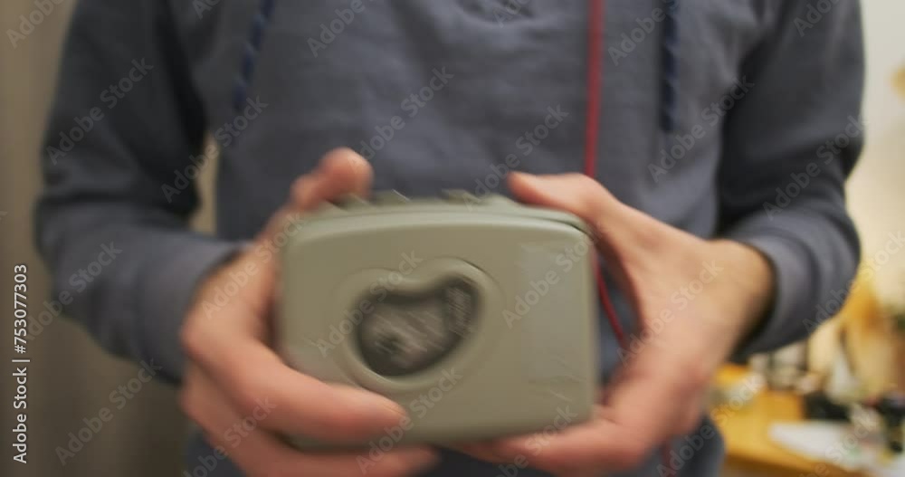 Unrecognizable man holds an old cassette player in his hands and rocks to the music. Concept of retro recording on magnetic tape, music, rhythm, dance. Unrecognizable man holds an old cassette player in his hands and rocks to the music. Concept of retro recording on magnetic tape, music, rhythm, dance.
