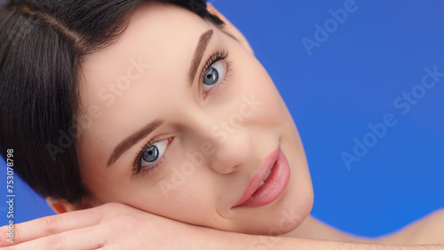 beautiful, young model rests her head on her hand, lying down and looking at the camera. The concept of healthy skin and female beauty, cosmetology services.
