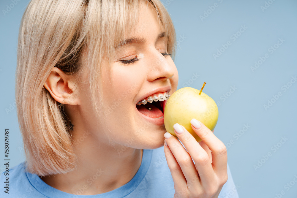 Closeup shot of gorgeous female wearing braces, enjoying an apple Closeup shot of gorgeous female wearing braces, enjoying an apple