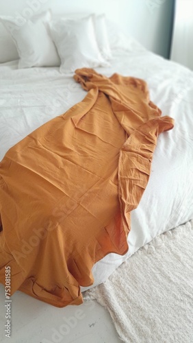 Cama en habitación aesthetic con sábana naranja.
