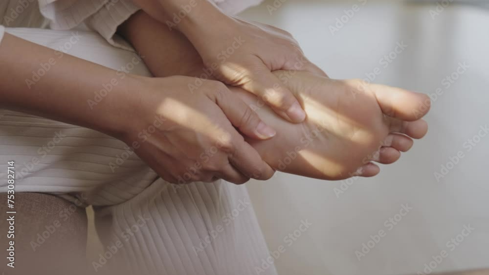Young Asian woman has pain in her feet from walking for a long time. Therefore, squeeze and massage to relieve the pain. Young Asian woman has pain in her feet from walking for a long time. Therefore, squeeze and massage to relieve the pain.