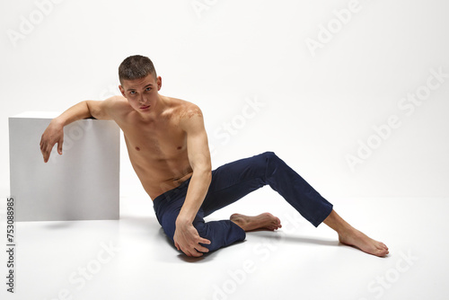 Handsome young guy with healthy, relief, muscular body posing in jeans isolated over white studio background. Concept of sportive lifestyle, body and heath care, youth