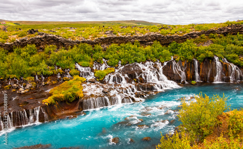 Panoramic view of Hraunfossar near Borgarfjörður (Iceland), a series of waterfalls and cascades formed by rivulets streaming out of a lava field. Major attraction with turquoise water in wild scenery.