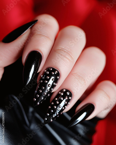 Rockstar glam nails, black leather effect, silver studs, edgy style. Glamour woman hand with nail polish on her fingernails. Nail art and design.