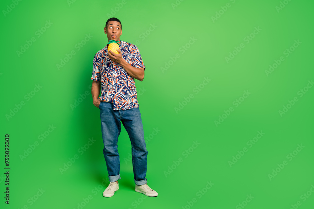 Full size portrait of nice funky person sipping straw pineapple cocktail look empty space isolated on green color background Full size portrait of nice funky person sipping straw pineapple cocktail look empty space isolated on green color background