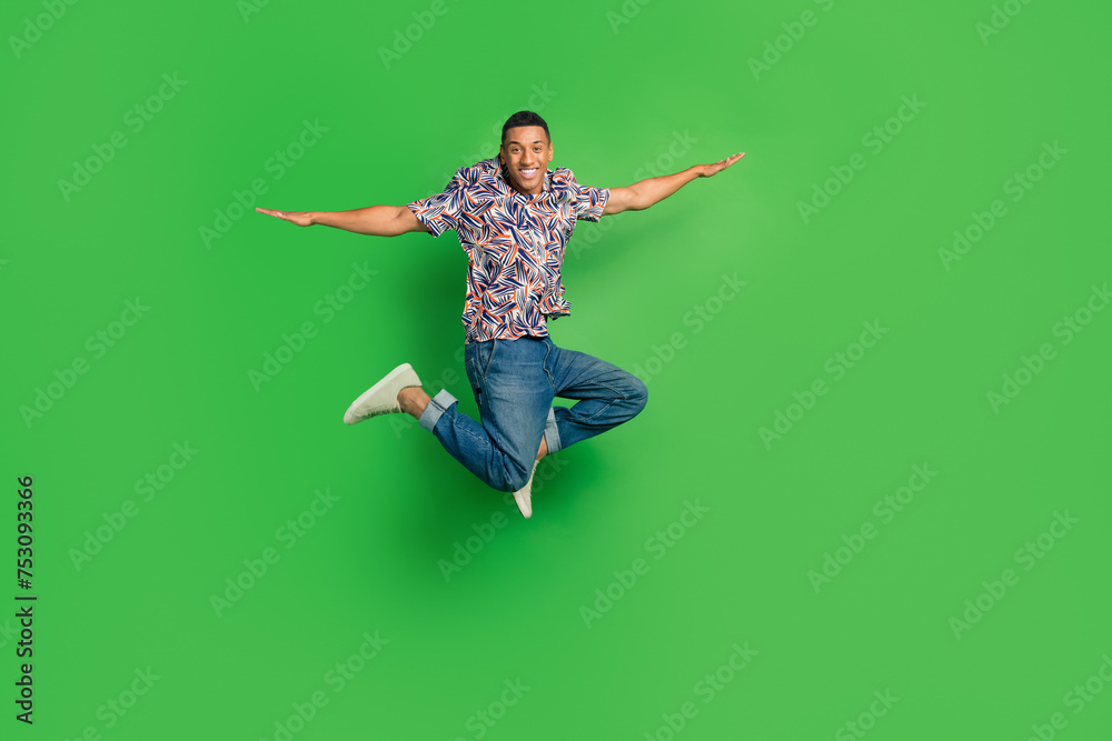 Full length photo of cheerful glad nice man wear trendy outfit fly air enjoy vacation isolated on green color background Full length photo of cheerful glad nice man wear trendy outfit fly air enjoy vacation isolated on green color background