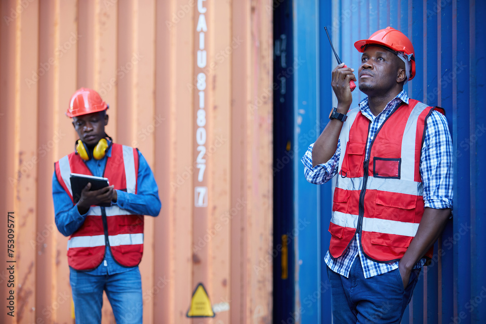African factory worker or engineer using walkie talkie and talking about work in containers warehouse storage