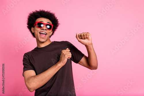 Portrait of carefree wavy hair man wear brown t shirt and sunglass rayban have fun chilling clubbing isolated on pink color background photo