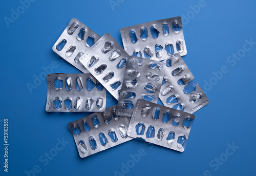 Used empty pill blister pack, discarded silver medicine packs, on blue background