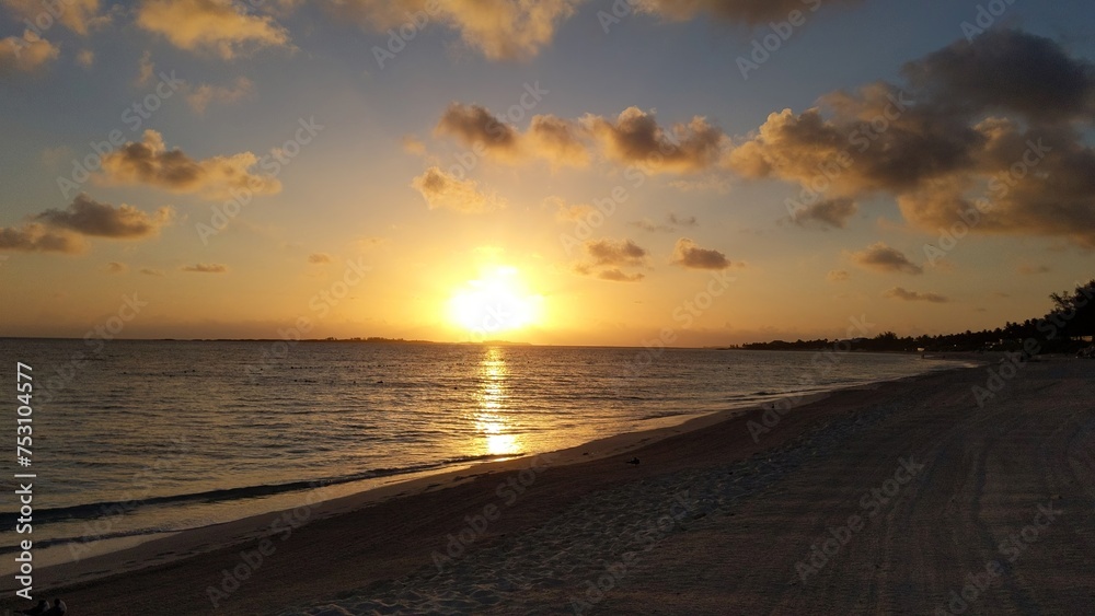 Obraz premium Serene Sunset Beach with Golden Reflections and Distant Shoreline