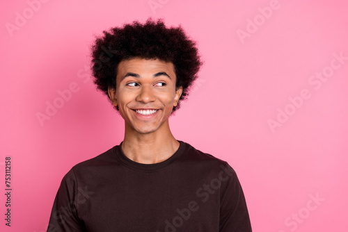 Portrait of cheerful happy young guy in brown t shirt looking empty space discount information advert isolated on pink color background