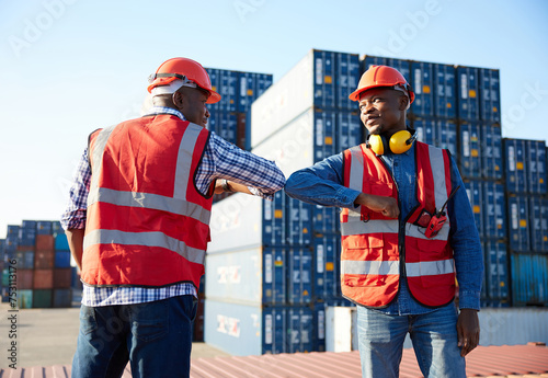 African factory workers or engineer greeting with elbow bumps in containers warehouse storage photo