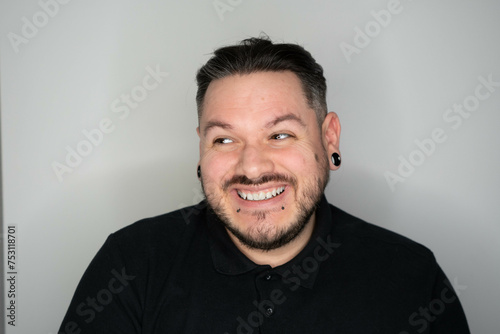 hombre con dilataciones sonriendo, hombre con tatuajes y dilataciones mirando a cámara, hombre con piercings sonriendo photo