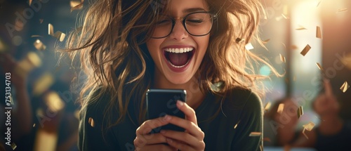 This young, happy woman, who won online, is holding her phone. She is feeling excited and is celebrating early success by receiving great news by sms or receiving a new job by smartphone. photo