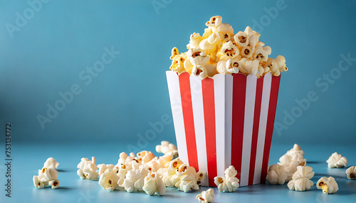 Popcorn in red and white cardboard box on blue background.