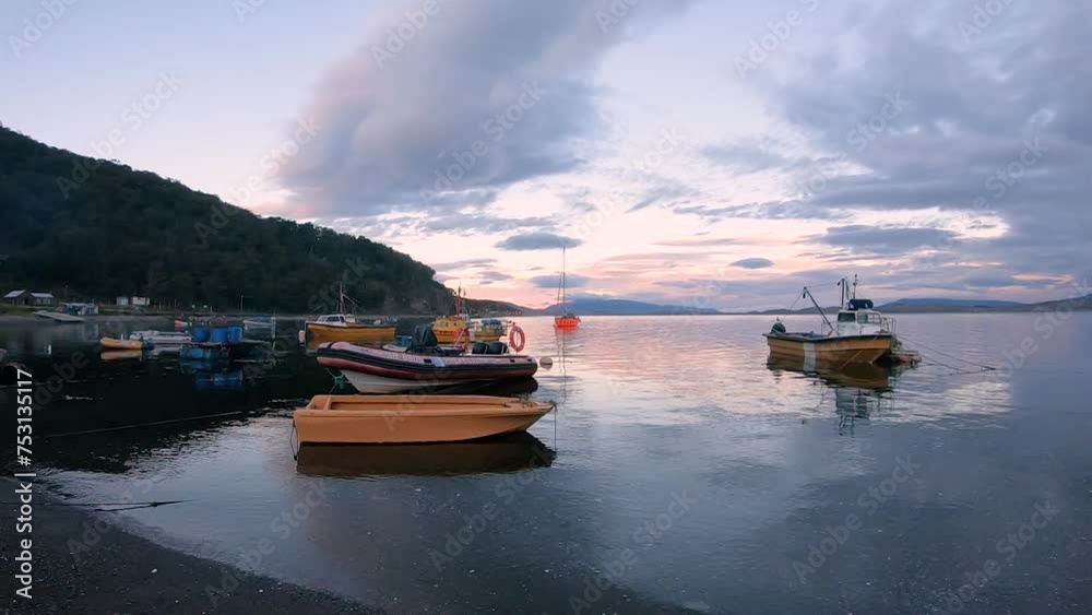 Panorama view of the fishing boats in Puerto Almanza harbor at sunset. View of the ships, shore, forest and mountains in the horizon under magical dusk sky.