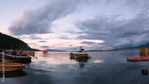 Panorama view of the fishing boats in Puerto Almanza harbor at sunset. View of the ships, shore, forest and mountains in the horizon under magical dusk sky.	
 photo