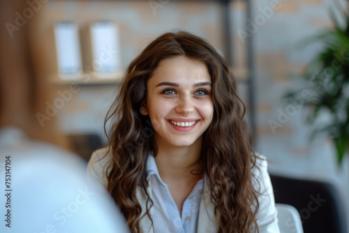 Free Download A woman, possibly a manager, sitting at a table with a smile on her face while interviewing new applicants in an office setting. - GFXLoad
