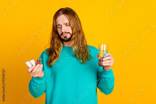 Photo of disappointed person look hand hold pills glass water empty space isolated on yellow color background