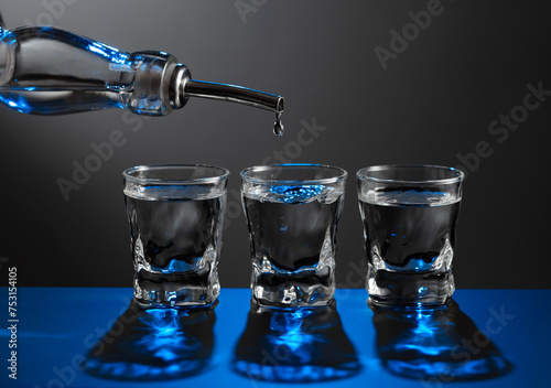 Vodka pouring from the bottle into a glass on a dark background.