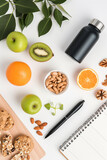 A flat lay of a fitness planner, water bottle, and healthy snack, isolated on a white background, to plan for success in weight loss