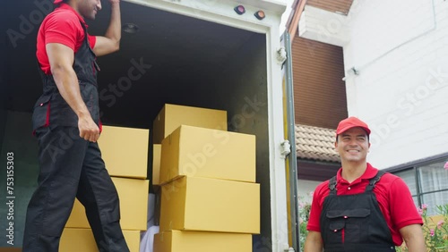 Side view of delivery man stand on truck and send parcel or box to his co-worker during transport the product to customer house.