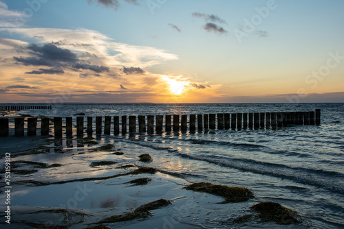 Sunset over the sea  with wooden groynes in the water