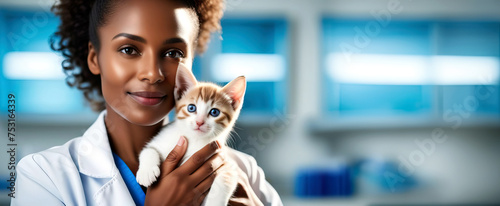 passionate and devoted dark-skinned veterinarian doctor with a fluffy kitten in a cuddle to which she has already become attached in the background of a medical office with space for a text photo