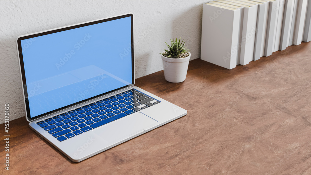 Laptop next to pot with plant near white books on wooden table, office and work theme Laptop next to pot with plant near white books on wooden table, office and work theme