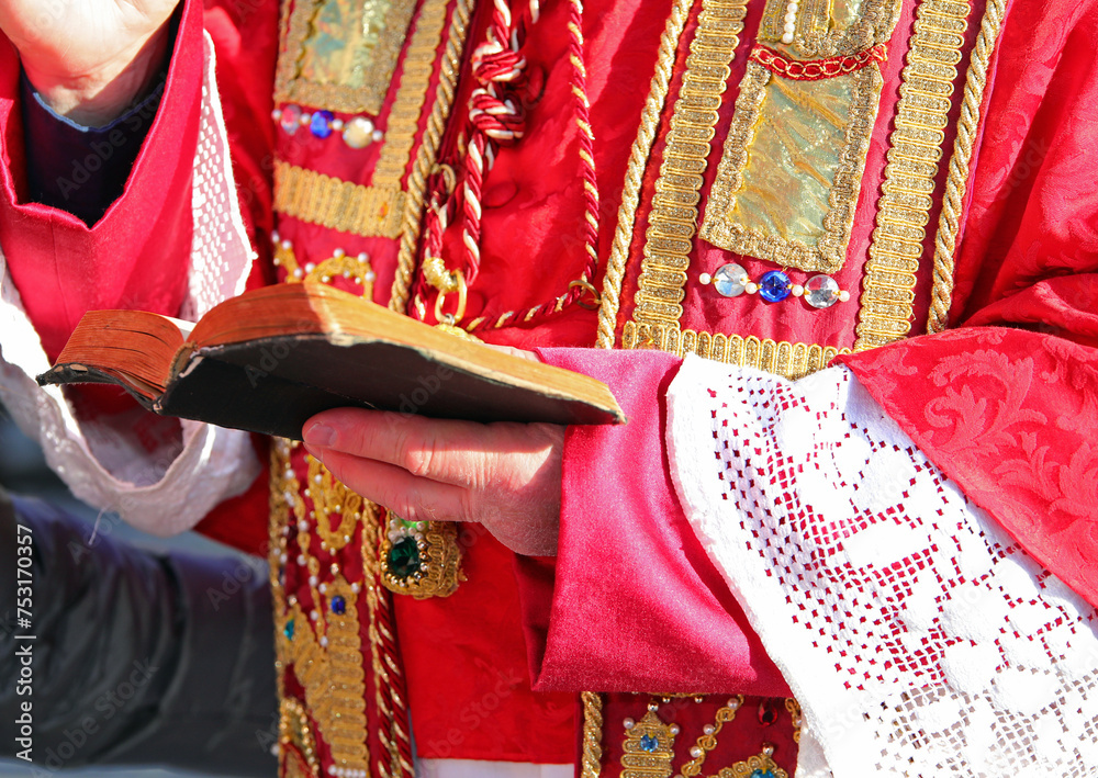 Religious Pastor in Red Vestments Blessing with Bible