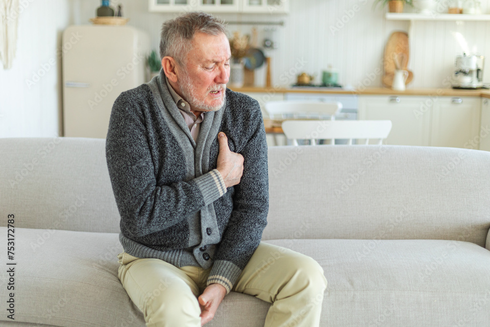 Pain on heart, heart attack. Unhappy middle aged senior man suffering from chest pain heart attack problems with health at home. Mature old senior grandfather touching chest experiencing infarction