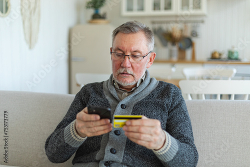Senior man shopping online holding smartphone paying with credit card. Old grandfather buying on Internet enter credit card details. Online shopping delivery service Older generation modern tech usage