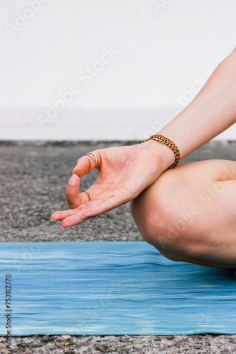 Lotus pose with mudra gesture. Woman practicing yoga on yoga mat, breathing and meditating. Wellbeing and mindfulness concept.