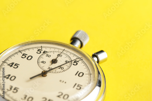 Mechanical stopwatch yellow background closeup.