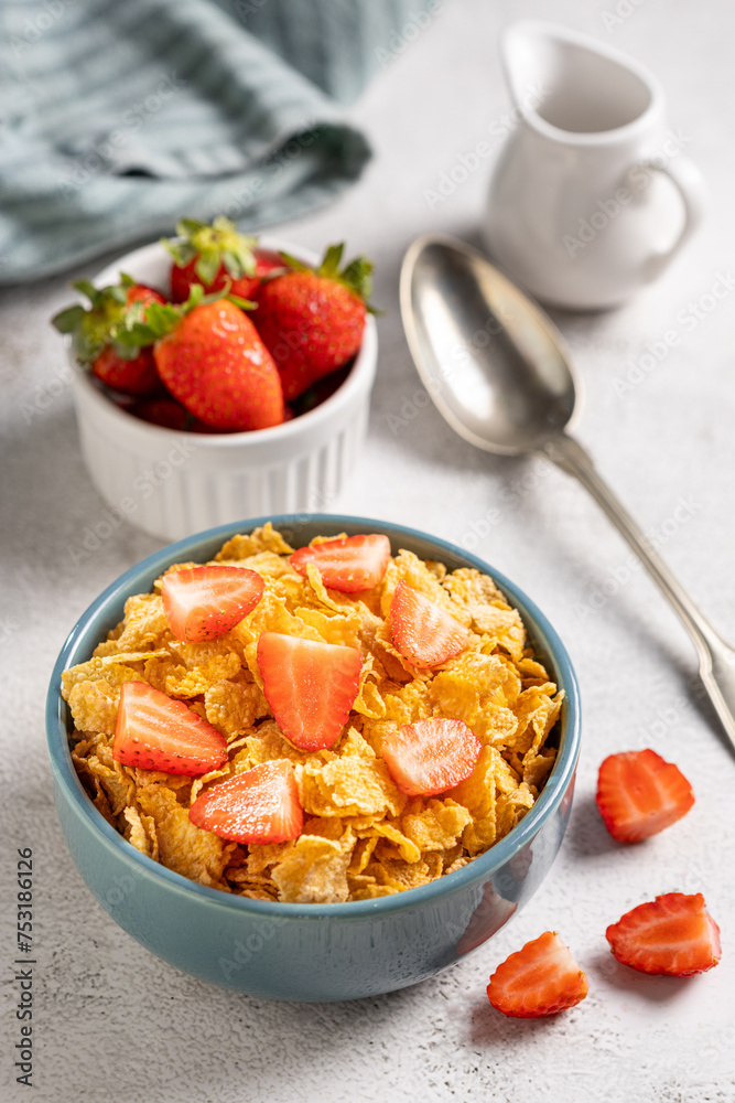 Bowl of corn flakes with sliced strawberries.