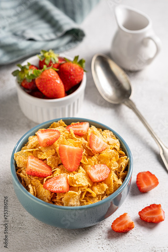 Bowl of corn flakes with sliced strawberries.